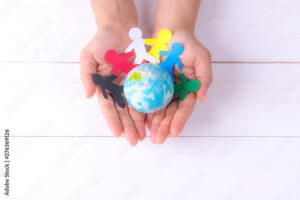 Woman holding globe with people chain made from paper cut. World population day.